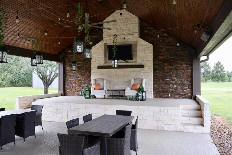 Custom pavilion with stone fireplace, TV mount, string lights, hanging lanterns, and dining area in Houston backyard